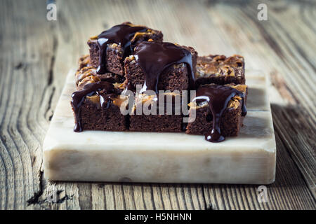 Homemade caramel chocolate brownies with dark chocolate ganache served on marble stand Stock Photo