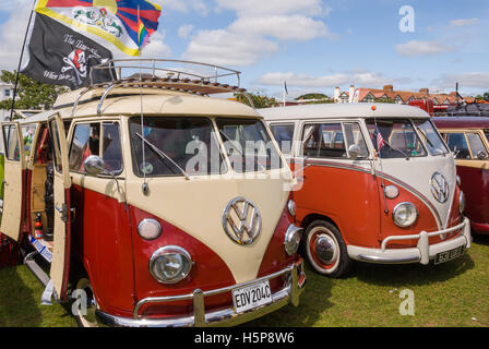 Two split screen VW camper vans on show at Paignton Green with a cloudy blue sky in the background Stock Photo