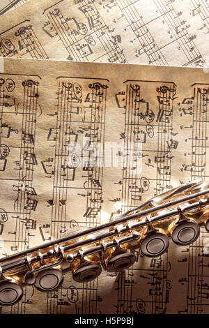Transverse flute in the bottom on old handwritten sheet music. Vertical composition. Top view Stock Photo