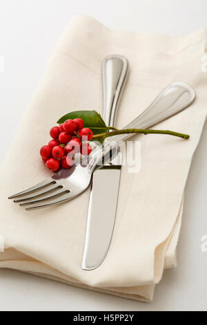 Simple, classic Christmas holiday table setting place setting with high quality silverware fork and knife on white linen napkin Stock Photo