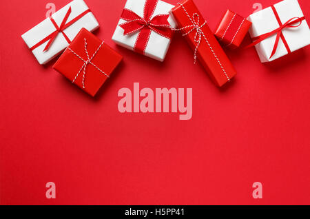 Christmas gifts presents on red background. Simple, classic, red & white wrapped gift boxes with ribbon bows horizontal border. Stock Photo