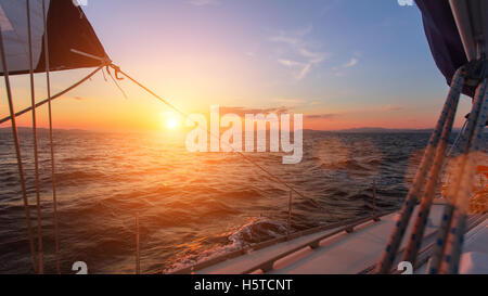 Beautiful sunset in the open sea with sailing yacht. Stock Photo