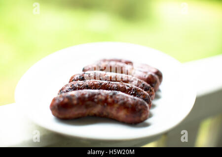 Some barbecued home made sausages on a white plate Stock Photo