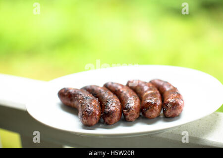 Some barbecued home made sausages on a white plate Stock Photo