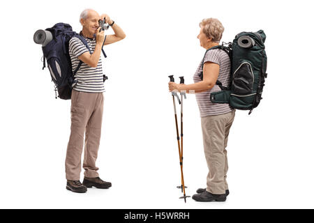 Elderly male hiker taking a picture with a camera of an elderly female hiker isolated on white background Stock Photo