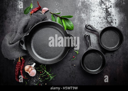 cast iron pan and spices on black metal culinary background, view from above Stock Photo