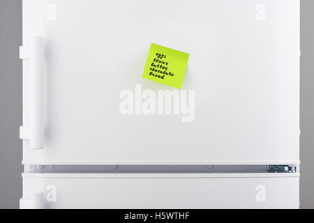 List of words eggs, flour, butter, chocolate, bread written on green sticky note paper on white refrigerator door Stock Photo