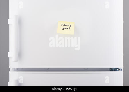 Thank you note on light yellow sticky paper on white refrigerator door Stock Photo