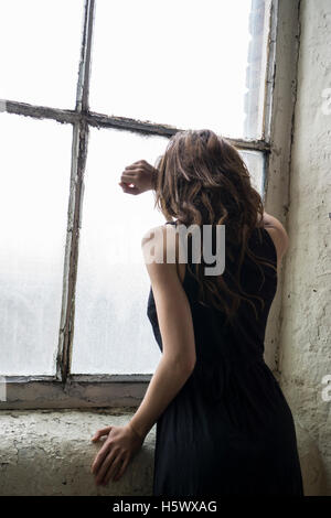 Sad woman leaning on the window Stock Photo