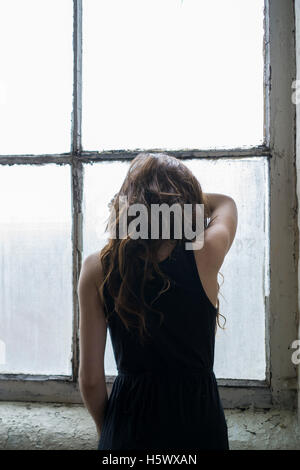 Sad woman leaning on the window Stock Photo