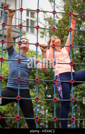 young sporty couple climbing up a net outdoors Stock Photo