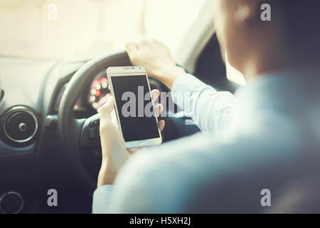 man using phone while driving the car (selective focus) - transportation and vehicle concept - vintage tone Stock Photo