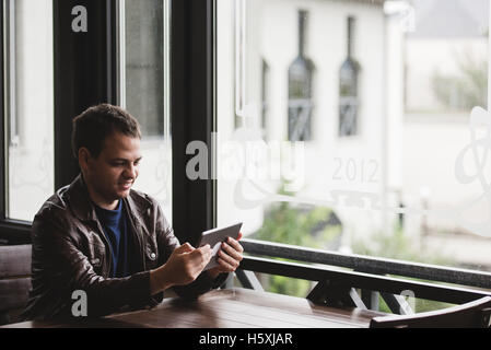 Young man sit in the city cafe during lunch time and working on tablet Stock Photo