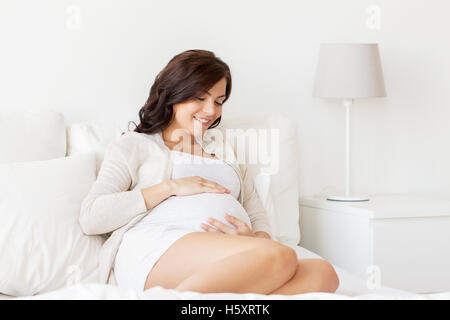 happy pregnant woman lying on bed at home Stock Photo