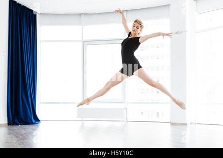 Graceful young woman ballerina dancing and jumping in ballet studio Stock Photo