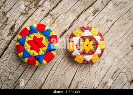 Two colorful Posamentenknöpfe, Schwälmer buttons, unique regional handicraft, laid on wooden panel Stock Photo