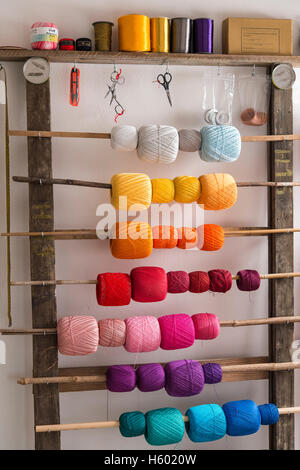 Colorful spools of thread for Posamentenknöpfe, hung on wooden shelf poles with scissors and ribbons, Ichenhausen, Bavaria Stock Photo