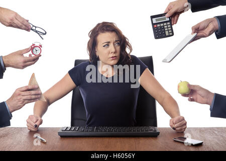 business woman sitting at her desk surrounded by many hands holding different objects Stock Photo