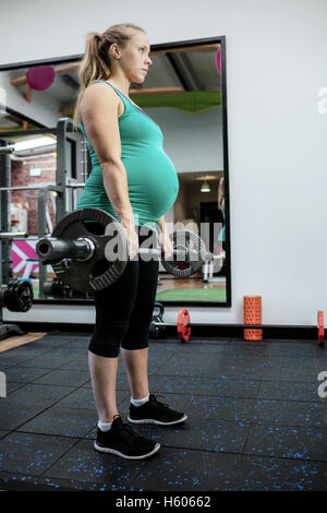 Pregnant woman working out with barbell Stock Photo