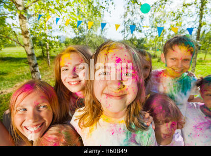 Happy kids' faces smeared with colored powder Stock Photo