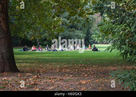 Yoga in the park Margaret, Budapest, Hungary. A group of young people under the guidance of an Asian woman doing yoga. Stock Photo