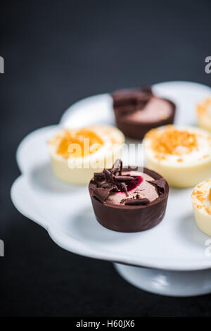 Belgian traditional chocolates hand decorated, overhead on dark slate Stock Photo