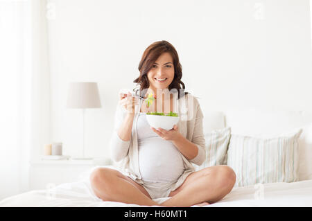 happy pregnant woman eating salad at home Stock Photo