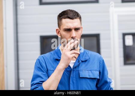 auto mechanic smoking cigarette at car workshop Stock Photo