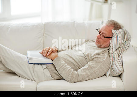 senior man sleeping on sofa with book at home Stock Photo
