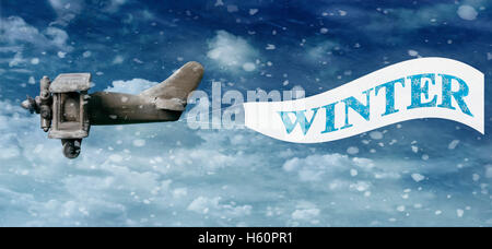 Vintage wooden toy plane pulling a Winter banner in snow filled sky Stock Photo