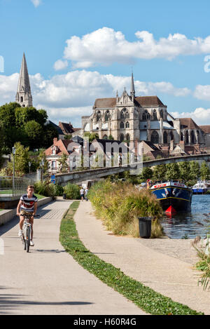 Visitors cycling away from Abbaye de Saint-Germain d'Auxerre in Auxerre on the towpath beside the river Yonne, Burgundy, France Stock Photo