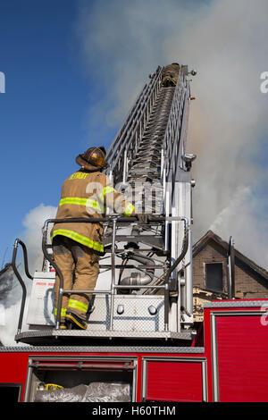 Firefighter operating Aerial ladder at scene of house fire, Detroit, Michigan USA Stock Photo