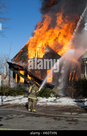 Firefighter extinguishing vacant house fire, Detroit, Michigan USA Stock Photo