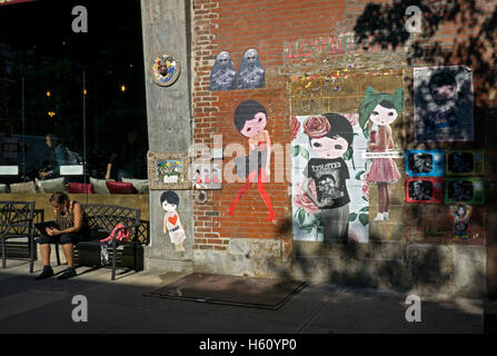 A wall with street art adjacent to a Second avenue coffee shop in the East Village, downtown Manhattan, New York City. Stock Photo