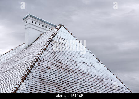 old tiled rooftop with chimney covered with snow Stock Photo