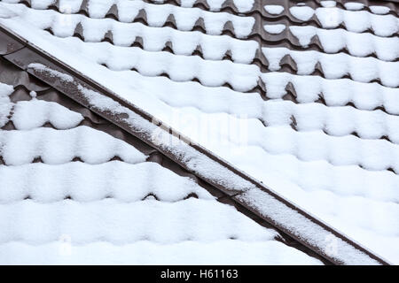 brown metal roof tiles covered with snow Stock Photo