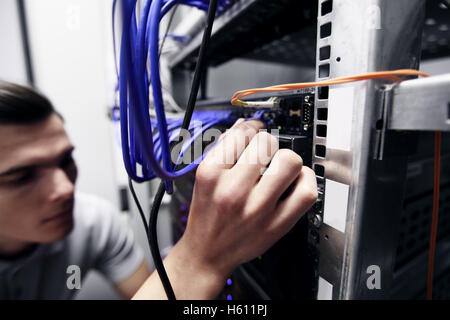 Young engeneer man in network server room connecting wires Stock Photo