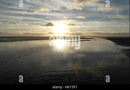 Whie sunset sky with cirrus and stratocumulus clouds reflecting in sea water channel on sand beach expanse, Fairhaven, Lytham Stock Photo