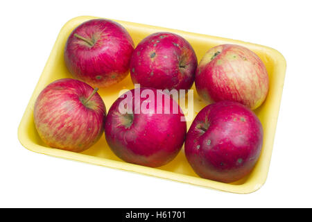Cheap red ugly apples of the lowest price category for poor people in yellow plastic container. Isolated with patch Stock Photo