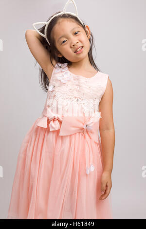 Child with cat ear headband in pink dress, isolated on white background. Stock Photo