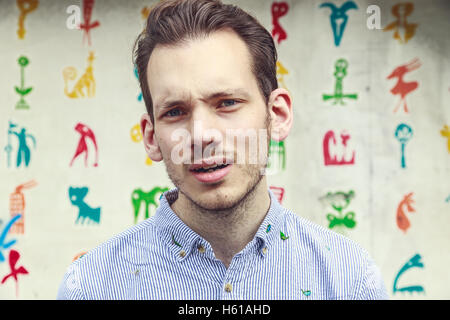 Portrait of a aggravated young man standing against a colourful funky background Stock Photo
