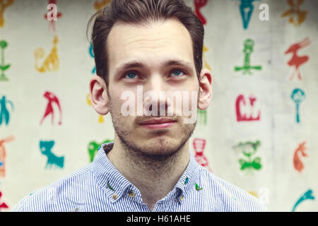 Portrait of a doubtful young man in front of a colourful funky background Stock Photo