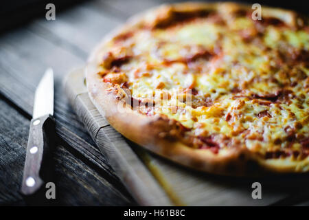 Pizza on the cutting board and knife beside Stock Photo