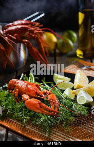 Boiled crayfish with fresh greens and a citrus on  black plate in style  rustic Stock Photo