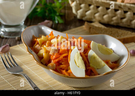 Salad of carrots in Korean, with cheese, egg and chicken meat on a wooden background. Stock Photo