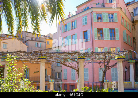 The colonnade in garden, located against the vintage houses in Place du Cap square in Menton, France Stock Photo