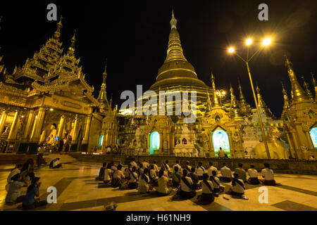 People praying in the Shwedagon Pagoda in Yangon at dusk Stock Photo