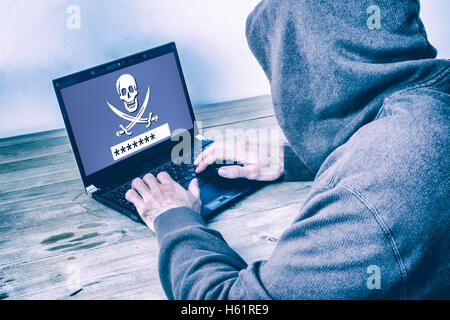Back view of a hacker wearing a hoodie and stealing a password on a laptop screen Stock Photo