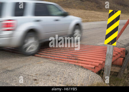 Vehicle crossing a cattle guard to control livestock movement between pastures on a rural road Stock Photo