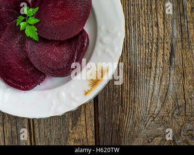 sliced boiled beets on white plate on an old weathered wooden table Stock Photo
